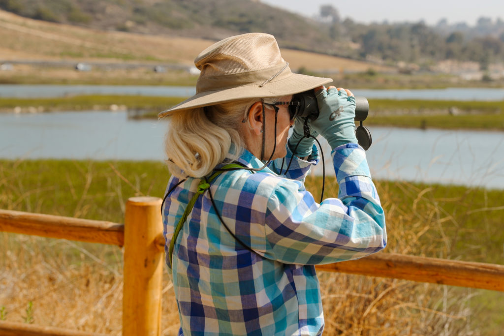A person with binoculars looks for birds at San Elijo Lagoon