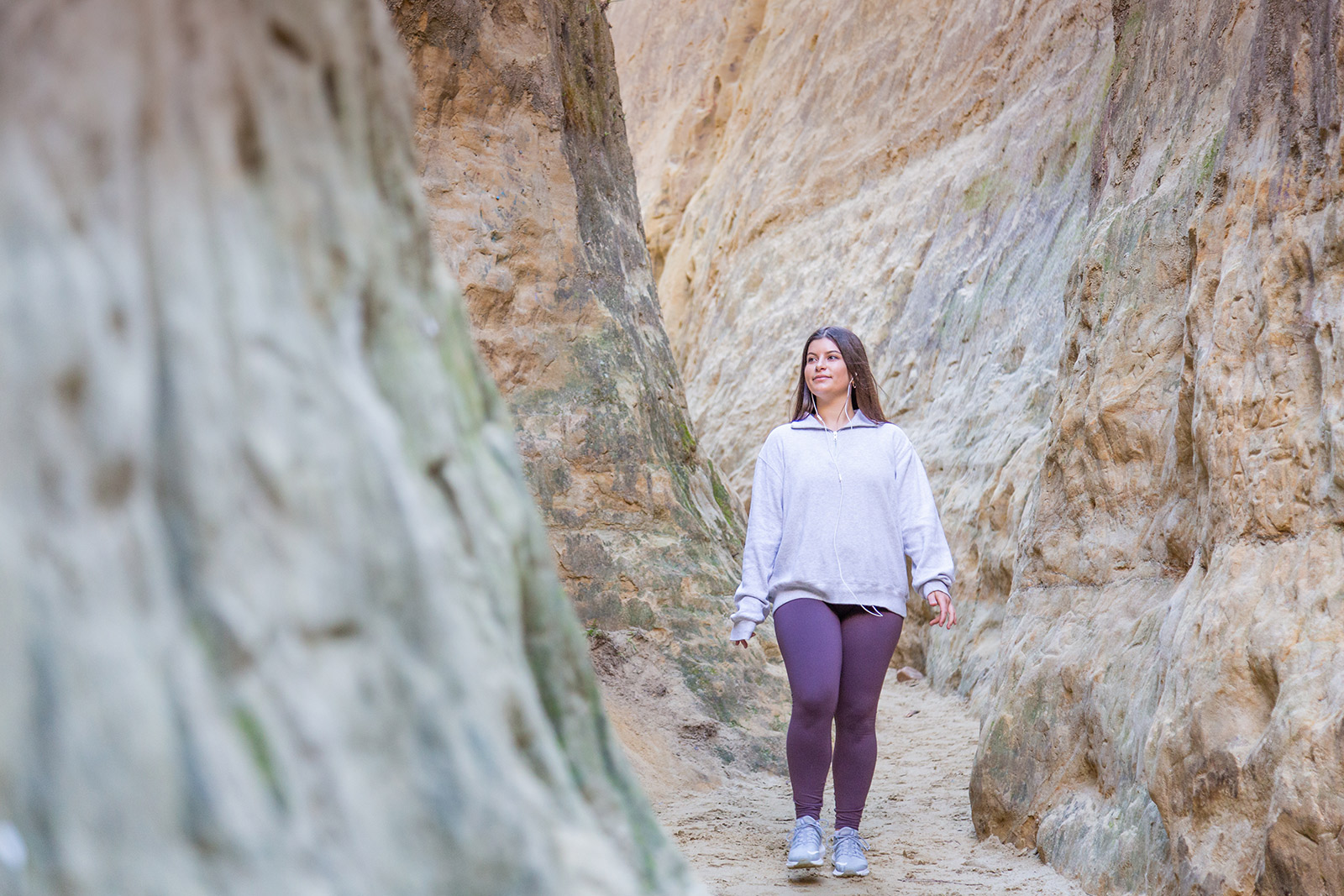 Woman walking through sandstone walled slot canyon