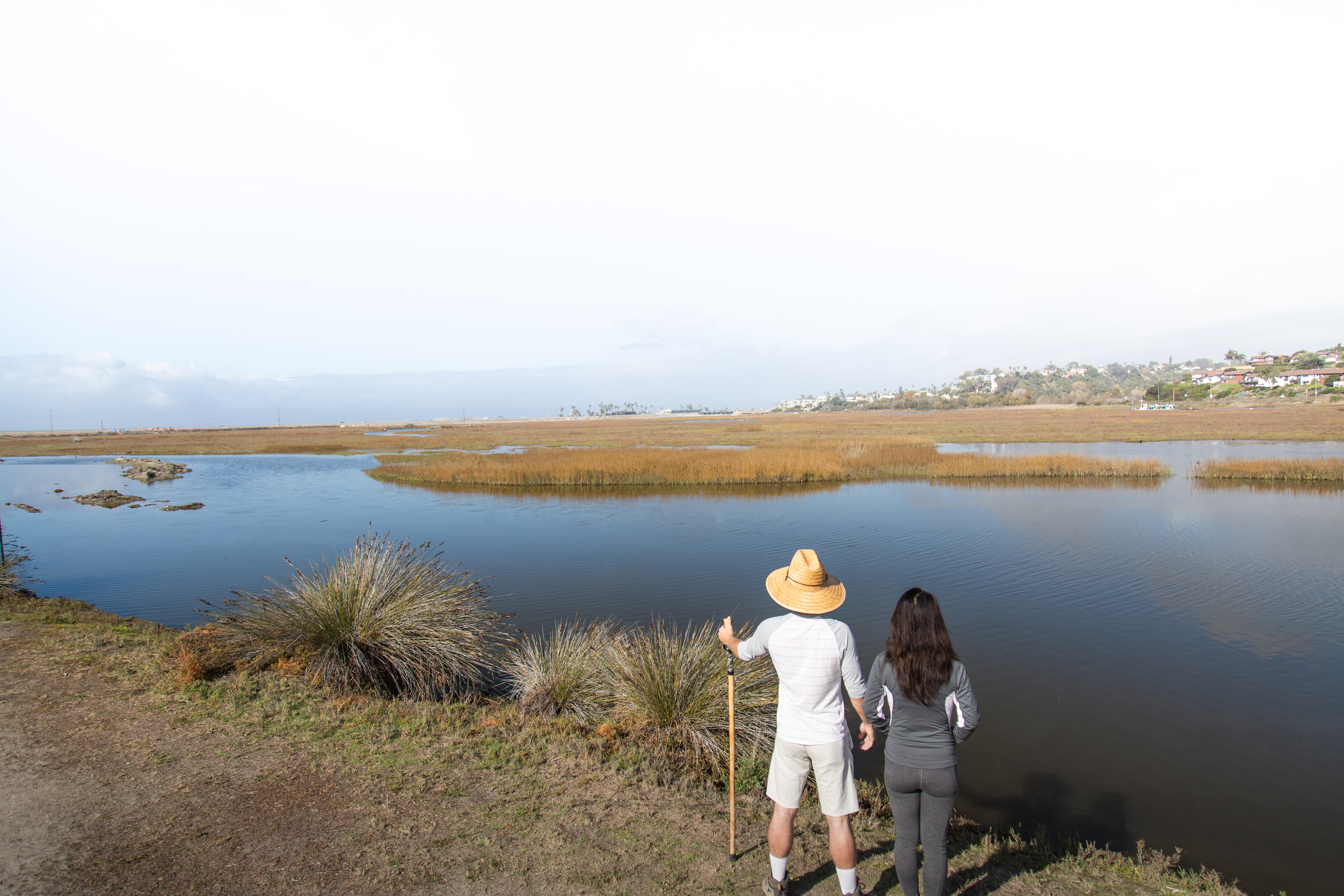 Man and woman stand at trailside overlooking the San Elijo Lagoon