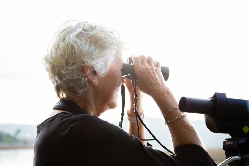 woman looks through binoculars at the horizon
