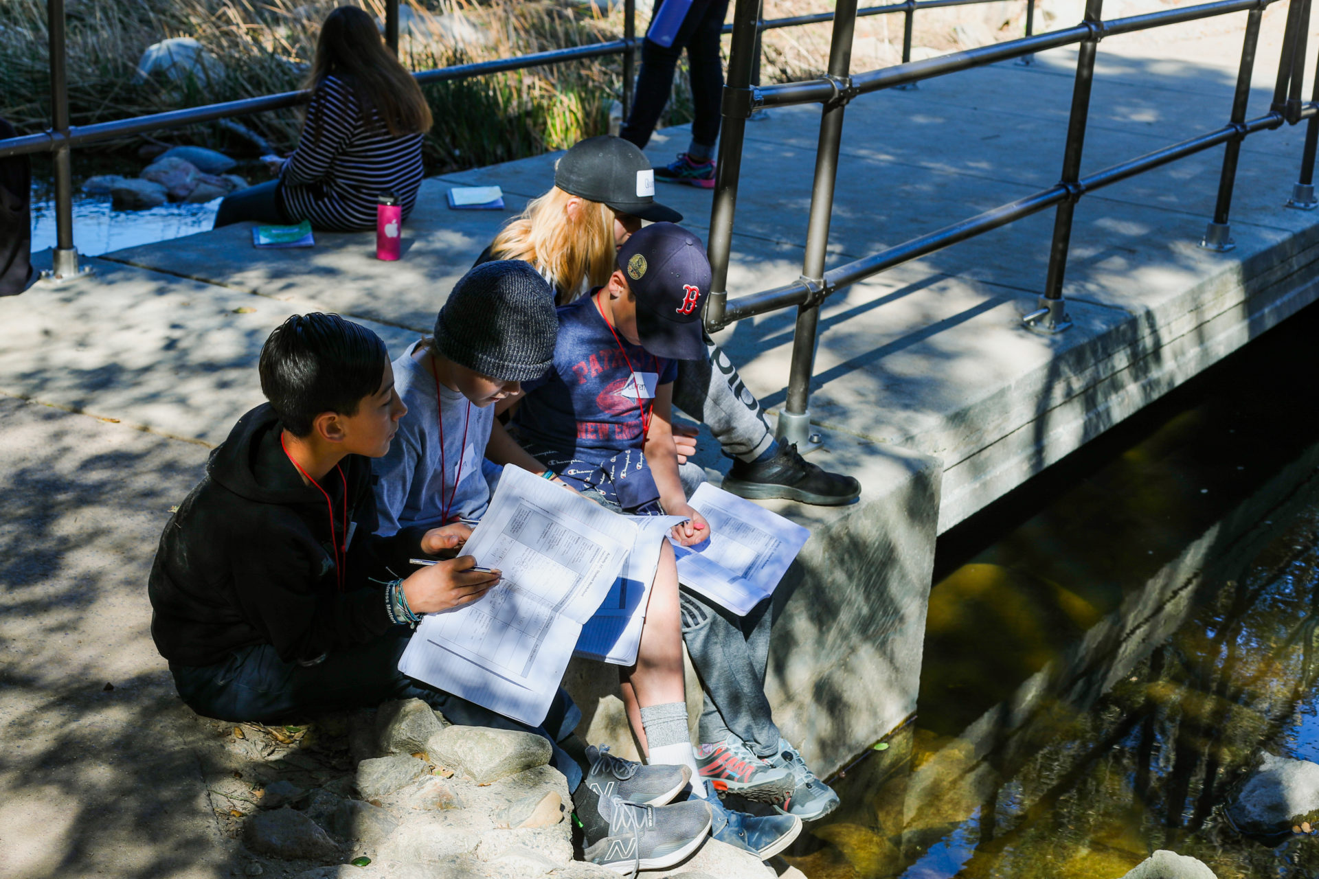 Group of students sitting at a bridge